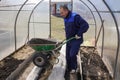 A man works in a vegetable garden in early spring. Digs the ground. Working in a greenhouse