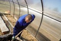 A man works in a vegetable garden in early spring. Digs the ground. Working in a greenhouse