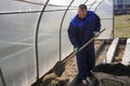 A man works in a vegetable garden in early spring. Digs the ground. Working in a greenhouse