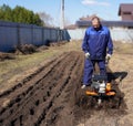 A man works in a vegetable garden in early spring. Digs the ground. Works as a cultivator, walk-behind tractor