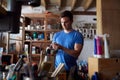 Man In Workshop Choosing Paintbrush For Upcycling And Craft Projects