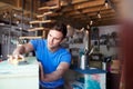 Man In Workshop Upcycling And Working On Furniture With Sandpaper