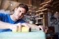 Man In Workshop Upcycling And Working On Furniture With Sandpaper