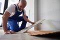 Man in workwear installing laminate flooring in apartment. Royalty Free Stock Photo