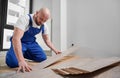 Man in workwear installing laminate flooring in apartment. Royalty Free Stock Photo