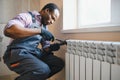 Man in workwear overalls using tools while installing or repairing heating radiator in room Royalty Free Stock Photo