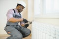 Man in workwear overalls using tools while installing or repairing heating radiator in room Royalty Free Stock Photo