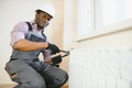 Man in workwear overalls using tools while installing or repairing heating radiator in room Royalty Free Stock Photo