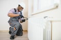 Man in workwear overalls using tools while installing or repairing heating radiator in room Royalty Free Stock Photo