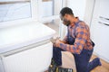 Man in workwear overalls using tools while installing or repairing heating radiator in room Royalty Free Stock Photo