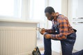 Man in workwear overalls using tools while installing or repairing heating radiator in room Royalty Free Stock Photo