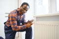 Man in workwear overalls using tools while installing or repairing heating radiator in room Royalty Free Stock Photo