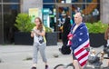 A man wrapped in a towel with an image of the American flag is walking down the street