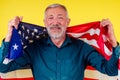 Man is wrapped waving american USA flag studio yellow background
