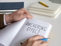 Man writes about anchoring effect or cognitive bias in notepad. Royalty Free Stock Photo