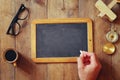 Man writes on a blank blackboard on wooden table