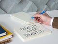 Man writes phrase quality over quantity on a page. Royalty Free Stock Photo
