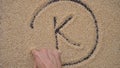 A man writes text on a black background using quinoa seeds. He writes text K as a symbol of the POTASSIUM microelement