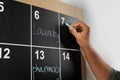 Man writing with chalk on board calendar, closeup