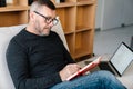 Man writing down notes while working with laptop