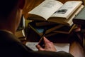 Looking over the shoulder of a man writing a letter while reading literary works