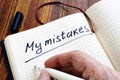 Man is writing My mistakes in a note. Inner critic.