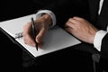 Man writing in notebook at black table, closeup Royalty Free Stock Photo