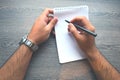 Man writing in a notebook.Top view of right handed man with metal silver watches and writing in notebook by black pen. Royalty Free Stock Photo