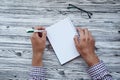 Man writing in notepad, using his left hand. Conceptual photo of lefthanded day. Mock up notepad. Top view. Copy space.