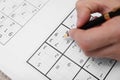 Man writing numbers in sudoku puzzle grid, closeup Royalty Free Stock Photo