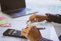 Man Writing paper and using calculator Calculating bonusOr other compensation to employees to increase productivity. on desk. Royalty Free Stock Photo