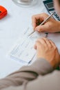 Man writing a payment check at the table with calculator and stamp Royalty Free Stock Photo