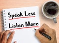 Man writing quote Speak less listen more on notebook with coffee on wood table background