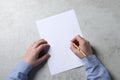 Man writing on sheet of paper with pen at light grey table, top view Royalty Free Stock Photo