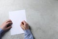 Man writing on sheet of paper with pen at light grey table, top view. Space for text Royalty Free Stock Photo