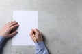 Man writing on sheet of paper with pen at light grey table, top view. Space for text Royalty Free Stock Photo