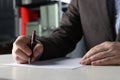 Man writing on sheet of paper with pen at white wooden table indoors, closeup Royalty Free Stock Photo