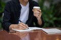 A man writing something in his book and sipping coffee at a table in a coffee shop Royalty Free Stock Photo