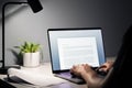Man writing text document, essay or letter with laptop. Freelance writer, journalist or entrepreneur working late at night. Royalty Free Stock Photo