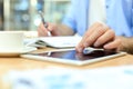 Man writing work plan with pen on paper notebook, browsing internet on digital tablet on office desk Royalty Free Stock Photo