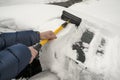 Man& x27;s arms with tool. Man cleaning snow off his car during winter snowfall