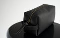 Man& x27;s black leather personal cosmetic bag or pouch for toiletry accessory on a black surface with white background Royalty Free Stock Photo