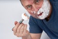 A man's face in shaving foam shaves with a safety razor Royalty Free Stock Photo