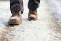 A man& x27;s feet in winter shoes take a step on a snowy road on a winter walk. Generative AI