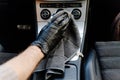 Man& x27;s hand in black glove cleaning car interior, dashboard and leather seats with microfiber cloth Royalty Free Stock Photo