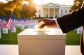 A man& x27;s hand drops his vote into the ballot box. American flags in the background, blurred background. Voting for Royalty Free Stock Photo
