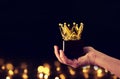 Man& x27;s hand holding crown award trophy for show victory or winning first place. Glitter overlay. Royalty Free Stock Photo