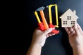 Man& x27;s hand holding wooden house toy and construction tools toy o Royalty Free Stock Photo