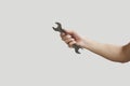 Man's hand holding wrench isolated over grey. Royalty Free Stock Photo