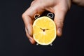 A man& x27;s hand holds a cut lemon, stylized as an alarm clock.